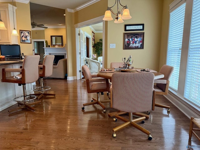 dining area featuring baseboards, ceiling fan with notable chandelier, crown molding, and wood finished floors