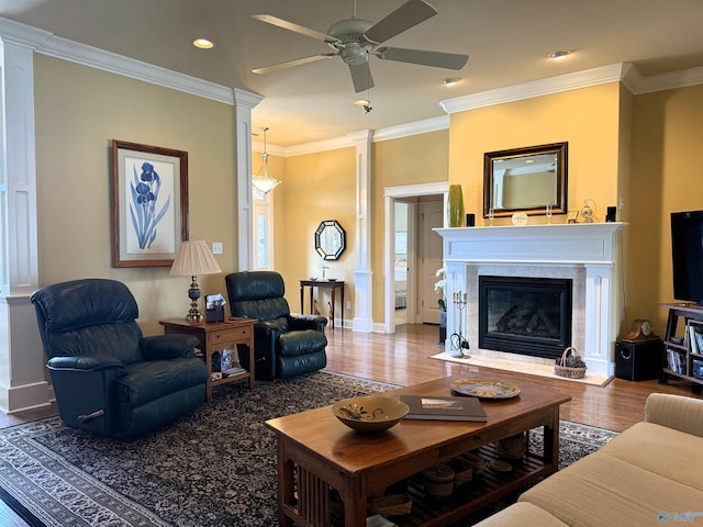 living area with wood finished floors, ceiling fan, crown molding, baseboards, and a fireplace with flush hearth