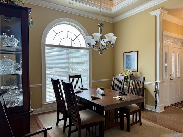 dining space with baseboards, ornamental molding, an inviting chandelier, visible vents, and wood finished floors