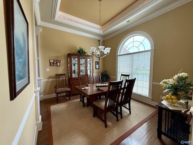 dining room with wood-type flooring, baseboards, a raised ceiling, a chandelier, and ornamental molding