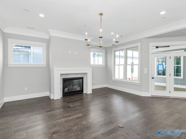 unfurnished living room featuring an inviting chandelier, crown molding, a high end fireplace, and dark wood-type flooring