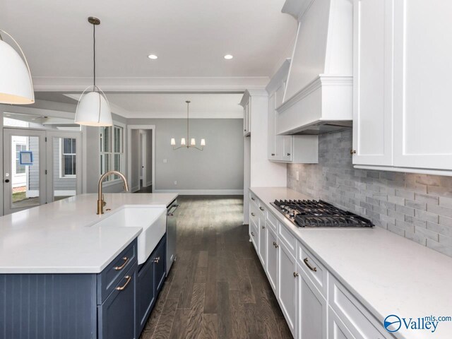 kitchen with premium range hood, blue cabinets, sink, hanging light fixtures, and stainless steel appliances