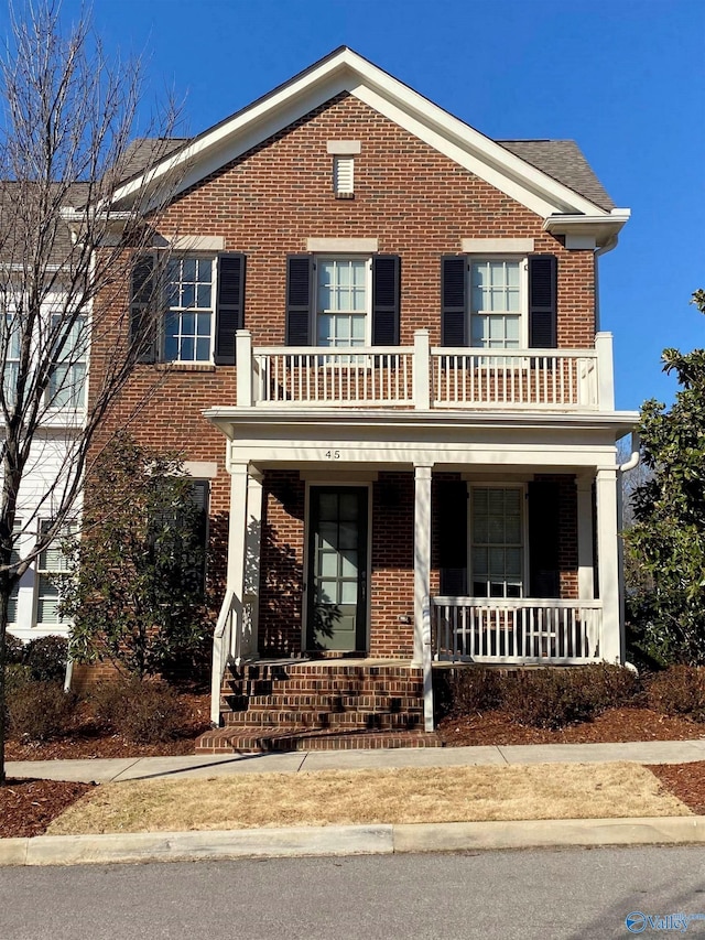 view of front facade with brick siding, a porch, and a balcony