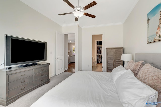 bedroom with ornamental molding, a ceiling fan, baseboards, light colored carpet, and a spacious closet