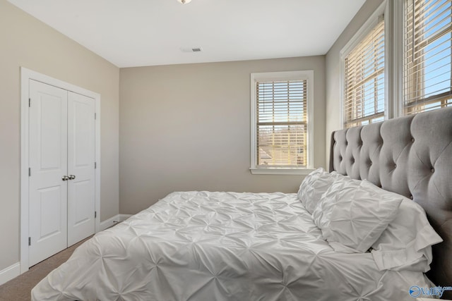 bedroom with visible vents, baseboards, carpet, and a closet