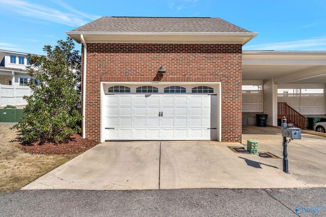 garage featuring concrete driveway and fence