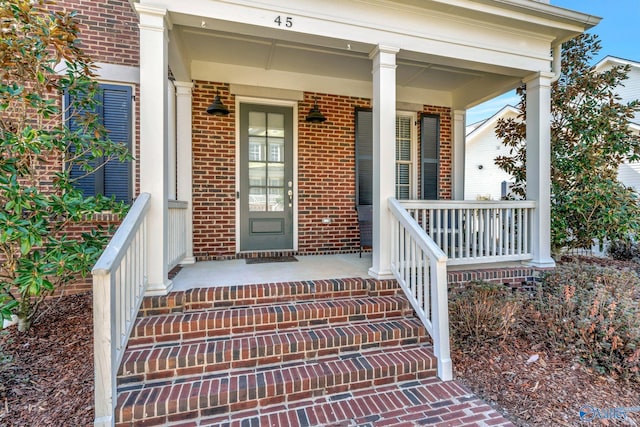 entrance to property with brick siding and a porch