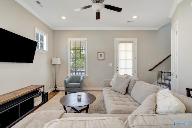 living area featuring visible vents, baseboards, ceiling fan, and crown molding