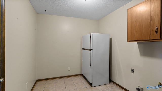2302 Auburn Dr, Decatur, AL 35603 - kitchen featuring freestanding refrigerator, a textured ceiling, baseboards, light tile patterned floors, and brown cabinetry