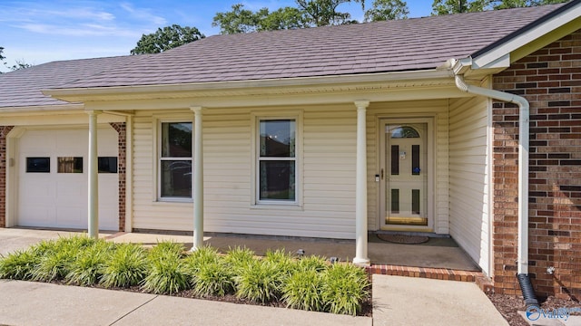 2302 Auburn Dr, Decatur, AL 35603 - property entrance featuring a porch, brick siding, an attached garage, concrete driveway, and a shingled roof