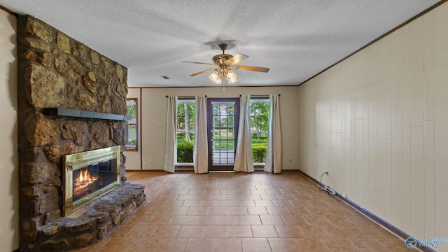 2302 Auburn Dr, Decatur, AL 35603 - unfurnished living room featuring baseboards, a stone fireplace, ceiling fan, a textured ceiling, and tile patterned flooring