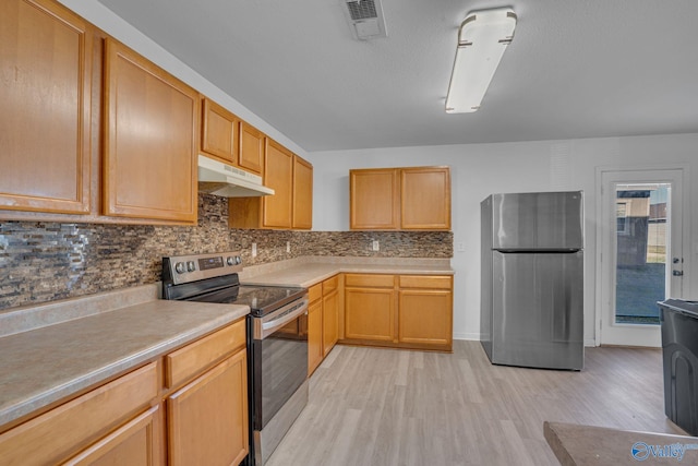 kitchen featuring light brown cabinets, light wood-type flooring, stainless steel appliances, and backsplash