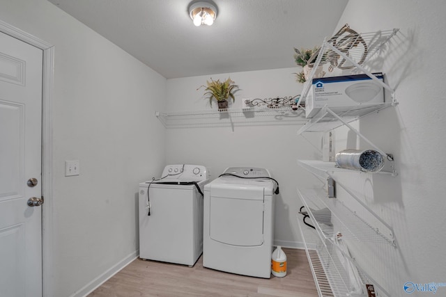 laundry room with washing machine and clothes dryer and light hardwood / wood-style flooring