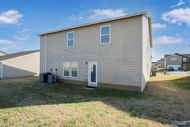 rear view of property featuring a lawn and central air condition unit