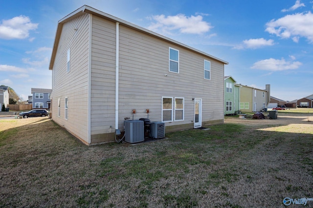 rear view of property with a yard and central AC