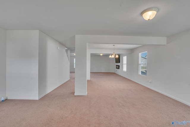 unfurnished living room with light colored carpet and an inviting chandelier