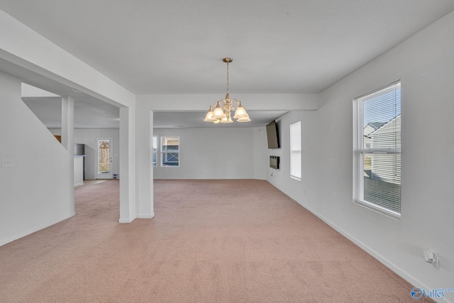 carpeted empty room featuring a notable chandelier