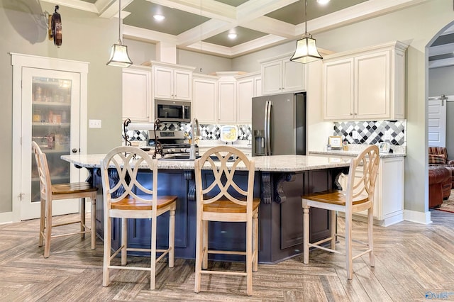 kitchen featuring backsplash, hanging light fixtures, light stone countertops, and stainless steel appliances