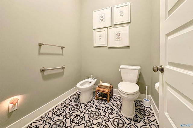 bathroom with toilet, a bidet, tile patterned flooring, and baseboards
