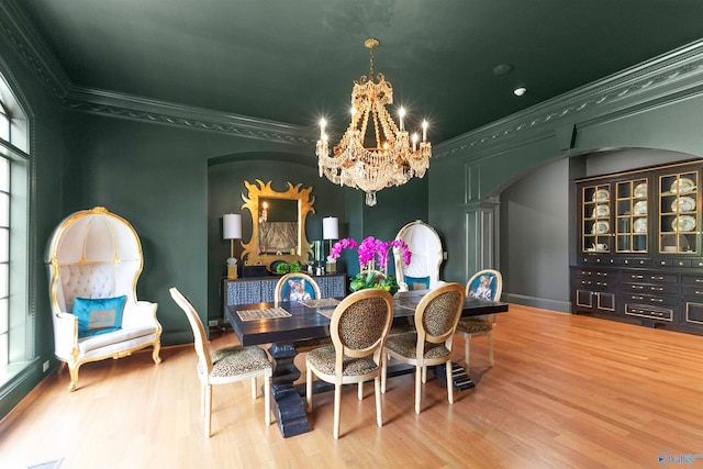 dining room with a notable chandelier, ornamental molding, hardwood / wood-style flooring, and decorative columns