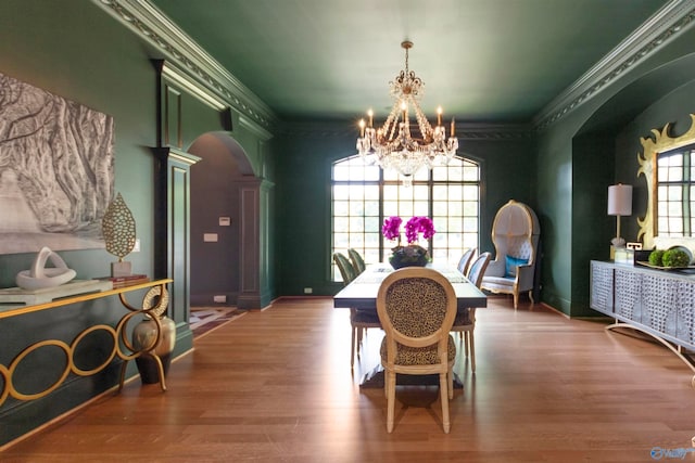 dining space featuring decorative columns, wood-type flooring, and ornamental molding