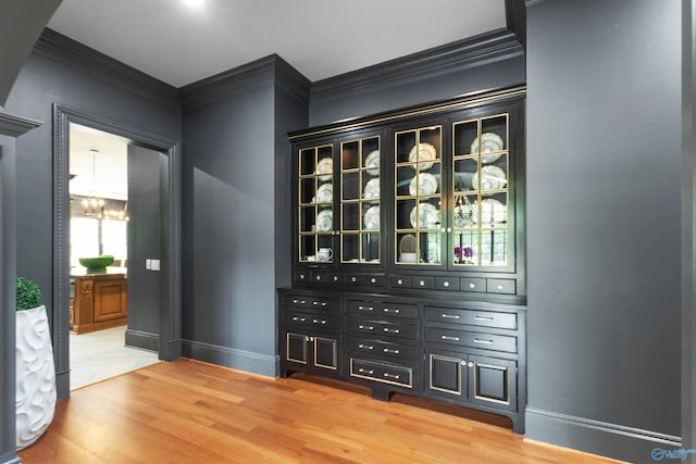 wine room with an inviting chandelier, crown molding, and hardwood / wood-style floors