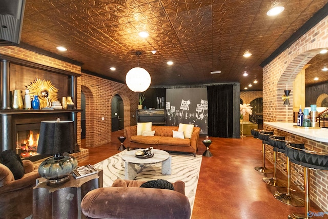 living room with brick wall, a fireplace, and concrete floors