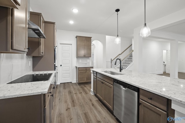 kitchen featuring decorative light fixtures, dishwasher, sink, backsplash, and wall chimney range hood