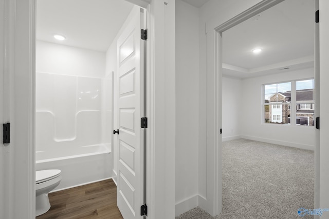 bathroom featuring shower / bath combination, toilet, a raised ceiling, and hardwood / wood-style floors