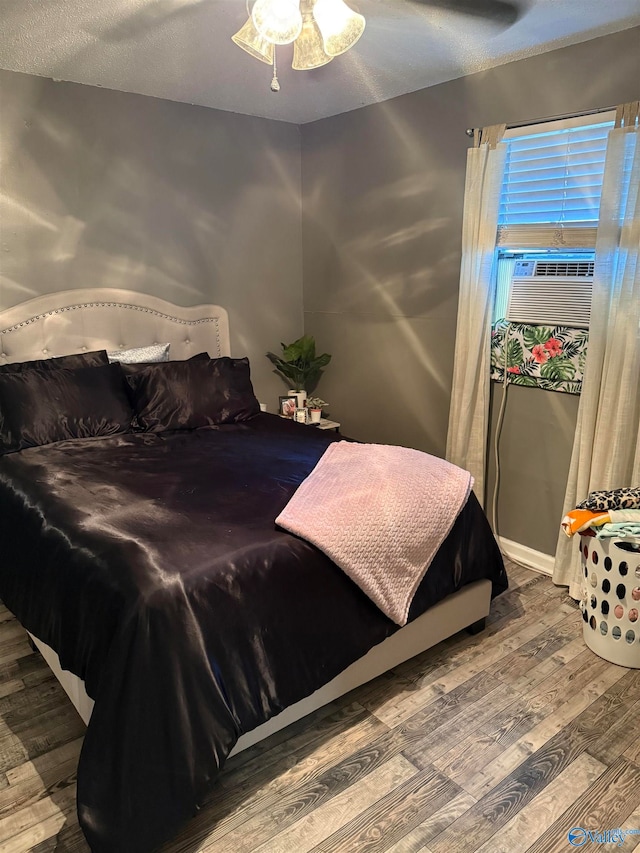 bedroom featuring a textured ceiling, cooling unit, hardwood / wood-style flooring, and ceiling fan