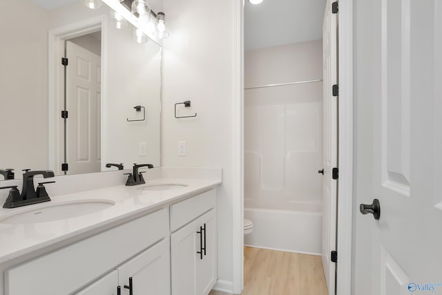 full bathroom with wood-type flooring, shower / washtub combination, vanity, and toilet