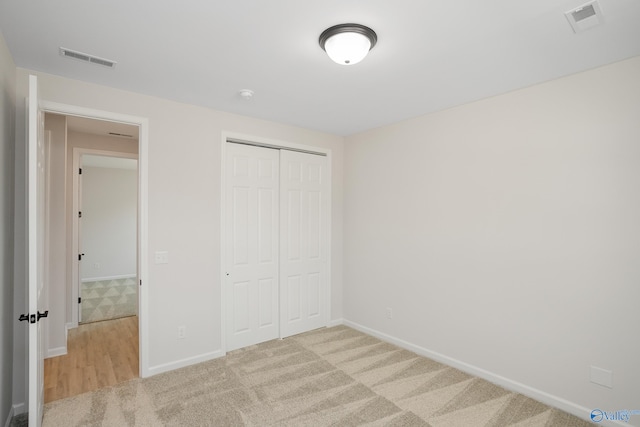 unfurnished bedroom featuring light carpet and a closet