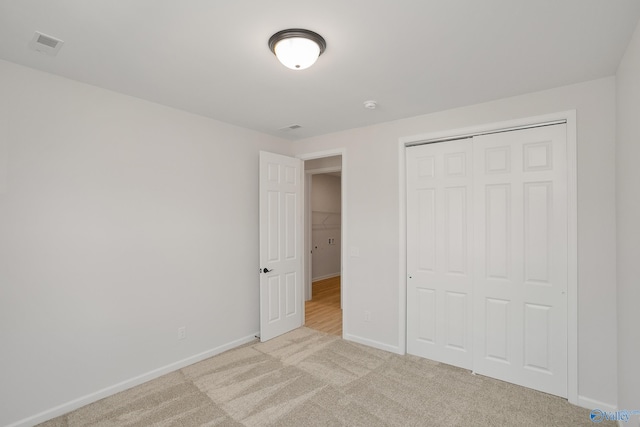 unfurnished bedroom with a closet and light carpet