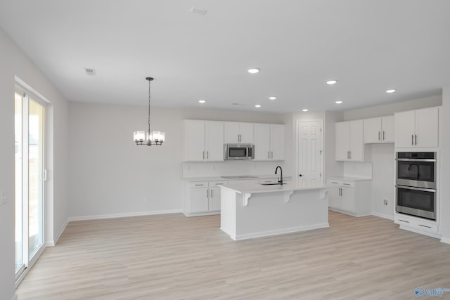 kitchen featuring stainless steel appliances, sink, a kitchen island with sink, and white cabinets