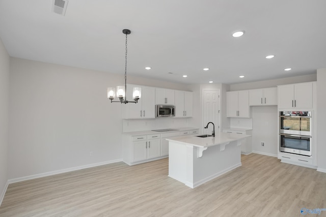 kitchen with white cabinetry, pendant lighting, stainless steel appliances, a kitchen island with sink, and decorative backsplash