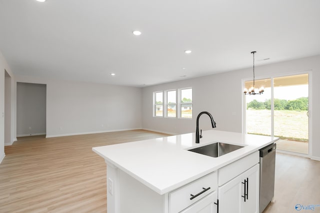 kitchen featuring sink, a center island with sink, stainless steel dishwasher, pendant lighting, and white cabinets