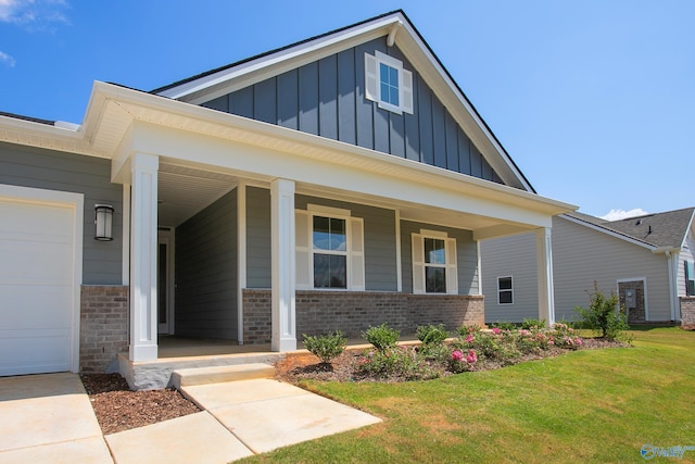 view of front of home with a garage, covered porch, and a front lawn