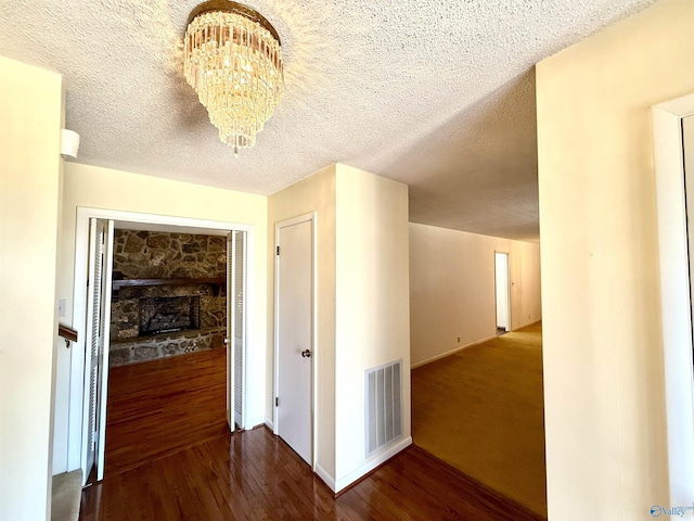 hall featuring hardwood / wood-style floors, a textured ceiling, and a notable chandelier