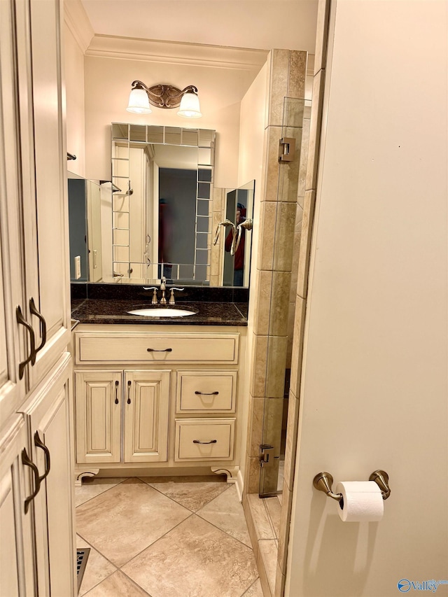 bathroom with a tile shower, vanity, and ornamental molding