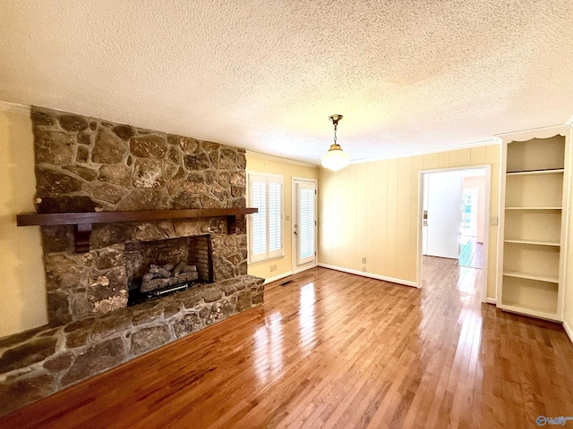 unfurnished living room featuring crown molding, a fireplace, hardwood / wood-style floors, and a textured ceiling