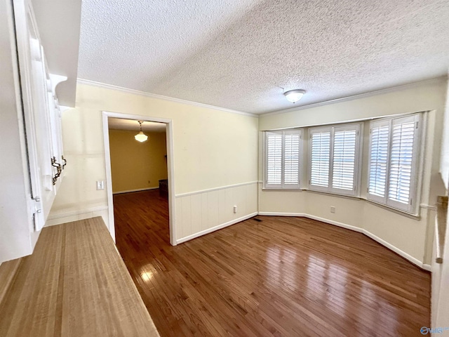 spare room featuring hardwood / wood-style flooring, ornamental molding, and a textured ceiling