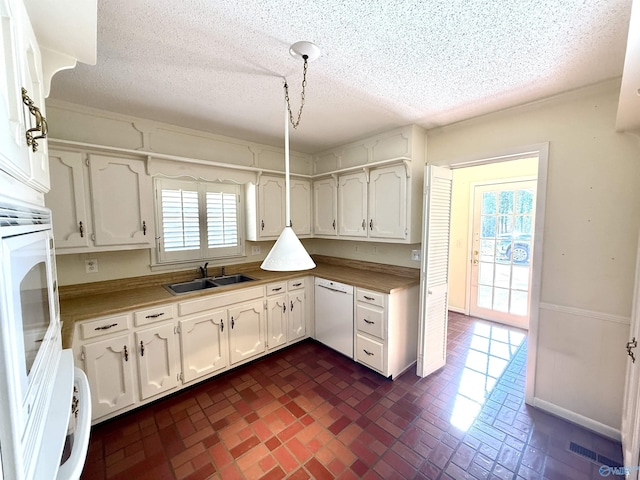 kitchen featuring white dishwasher, sink, a textured ceiling, and white cabinets