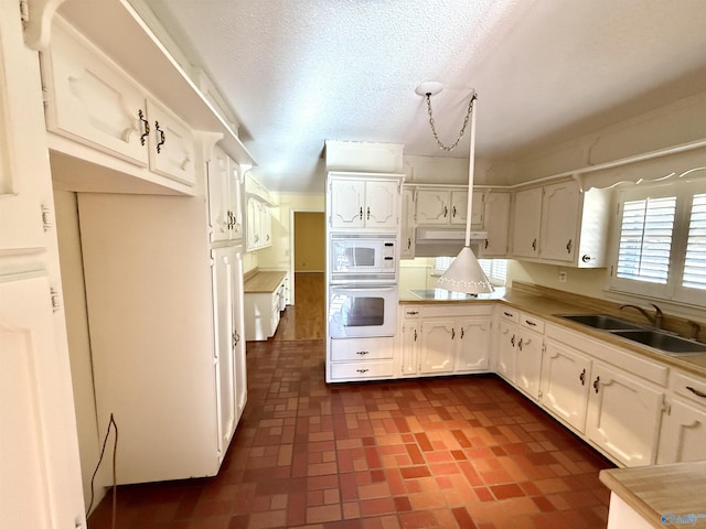 kitchen with sink, a textured ceiling, white cabinets, and white appliances