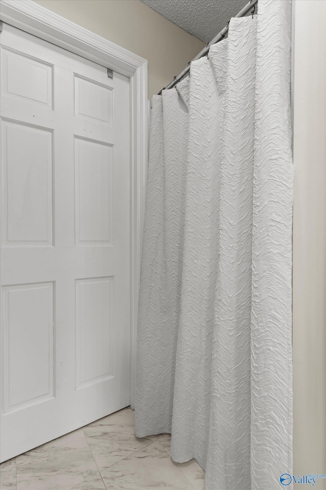 2413 Remington Cir SW, Decatur, AL 35601 - bathroom with marble finish floors, a textured ceiling, and a shower with shower curtain