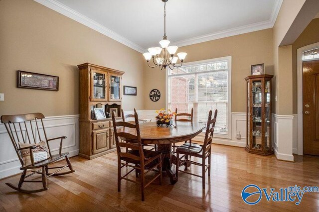 dining room with a notable chandelier, ornamental molding, and light hardwood / wood-style floors