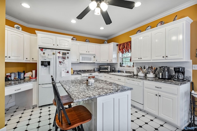 kitchen with a kitchen island, white cabinetry, sink, a kitchen bar, and white appliances