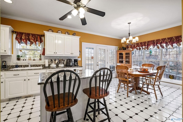 kitchen featuring a kitchen island, sink, dark stone countertops, and white cabinets