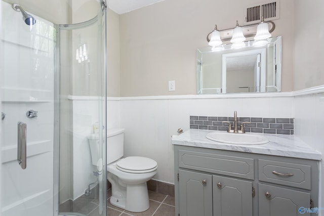 bathroom with vanity, decorative backsplash, a shower with shower door, tile patterned floors, and toilet