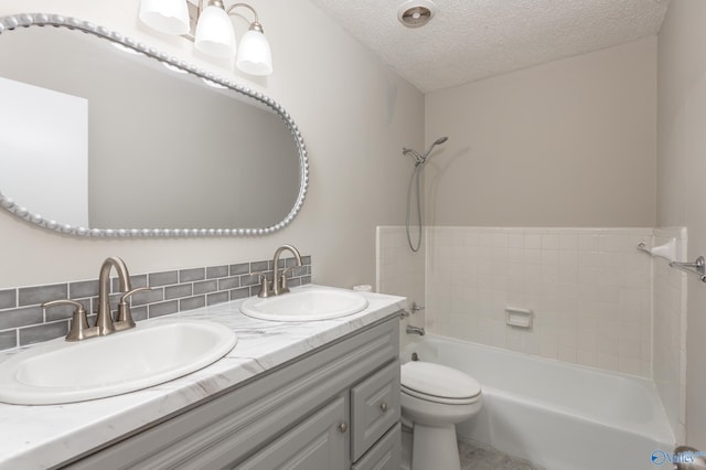 full bathroom with shower / washtub combination, dual bowl vanity, a textured ceiling, backsplash, and toilet