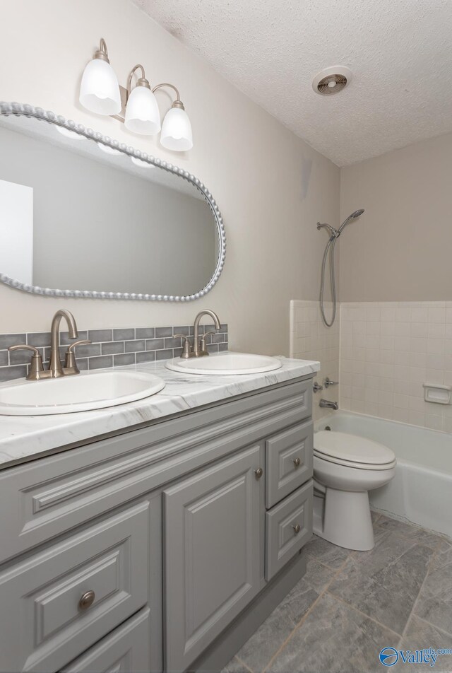 full bathroom featuring dual vanity, bathtub / shower combination, tile patterned flooring, a textured ceiling, and toilet